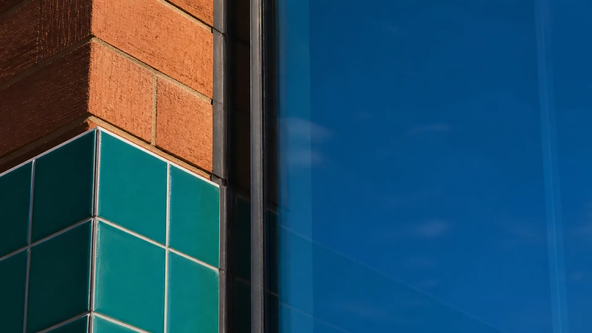 Brick, glazed tile and cobalt glass meeting in a precise seam