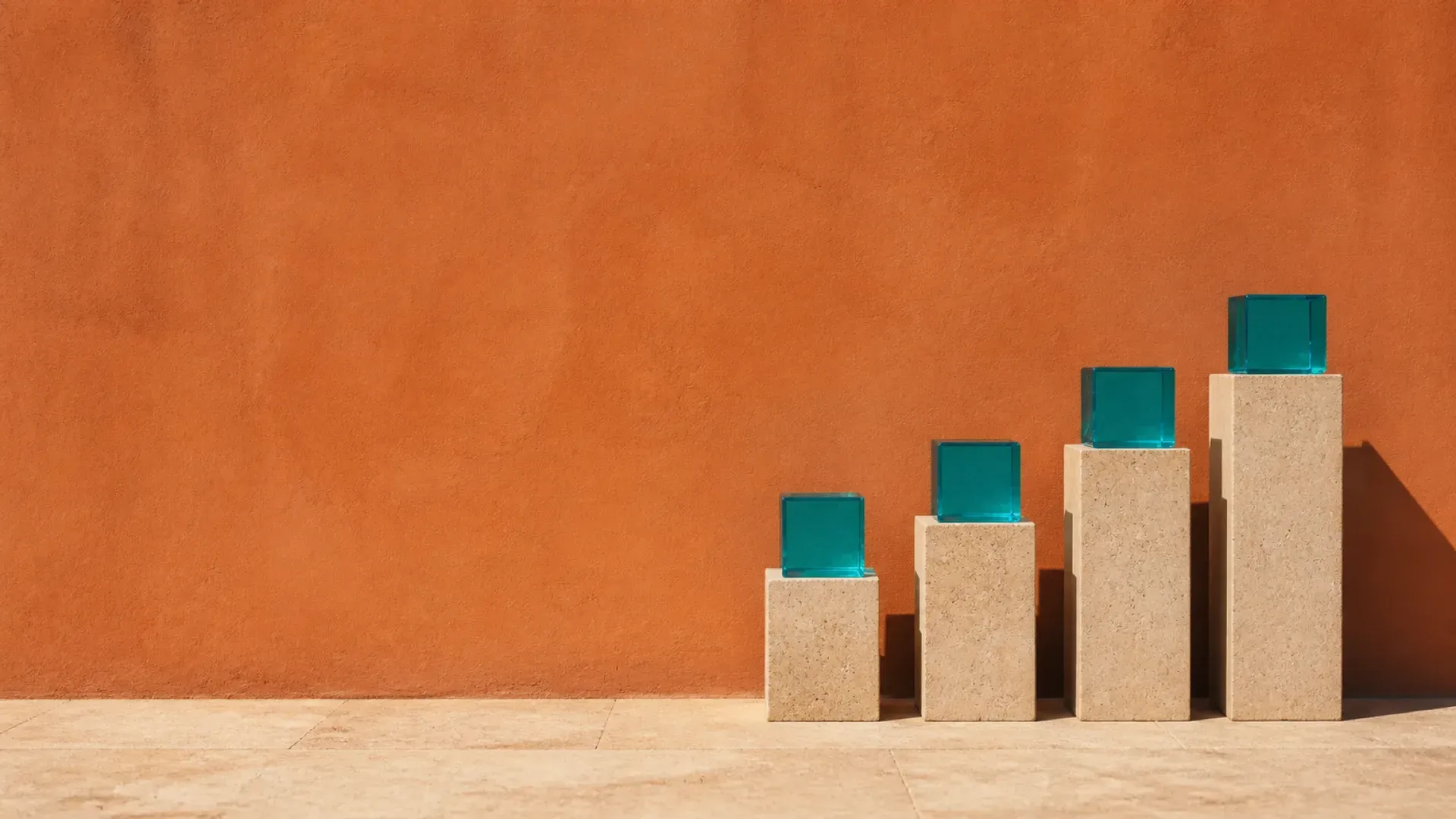 Four stone plinths rising in steps, each carrying a turquoise glass block