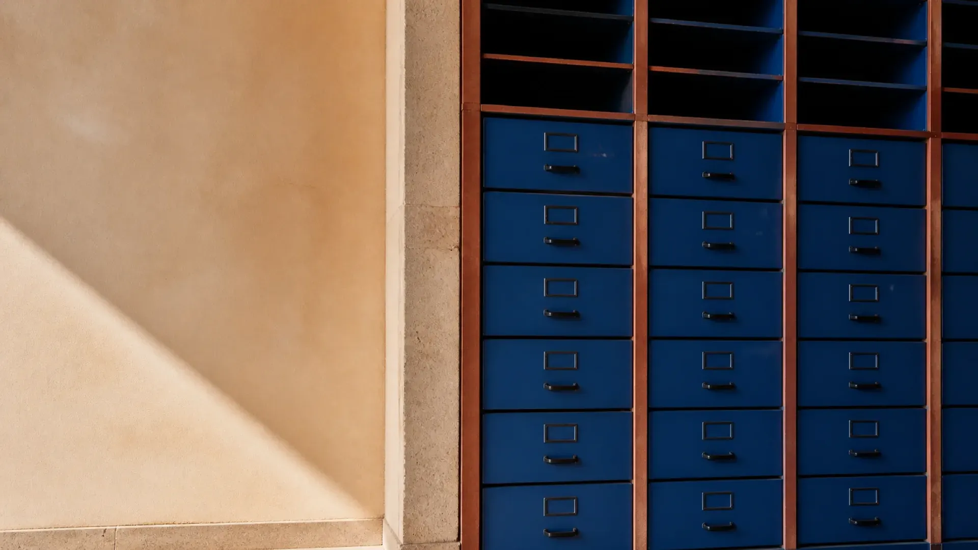 A wall of cobalt filing drawers and open cubbies with stone and terracotta dividers